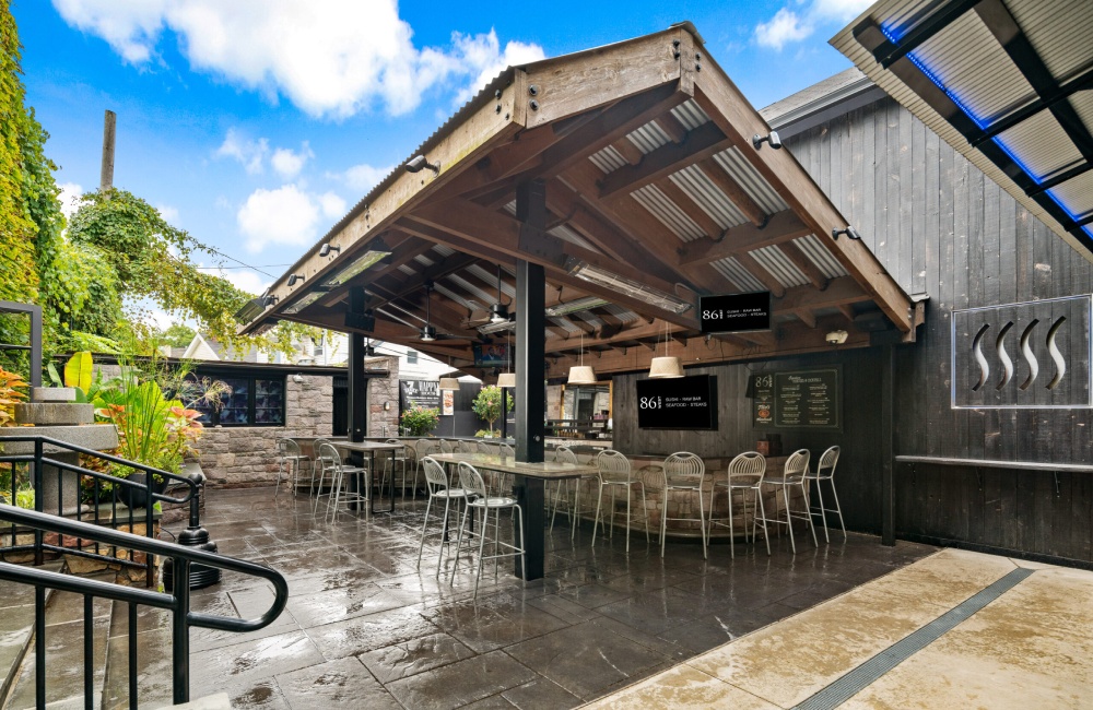 An outdoor patio with a bar and chairs.